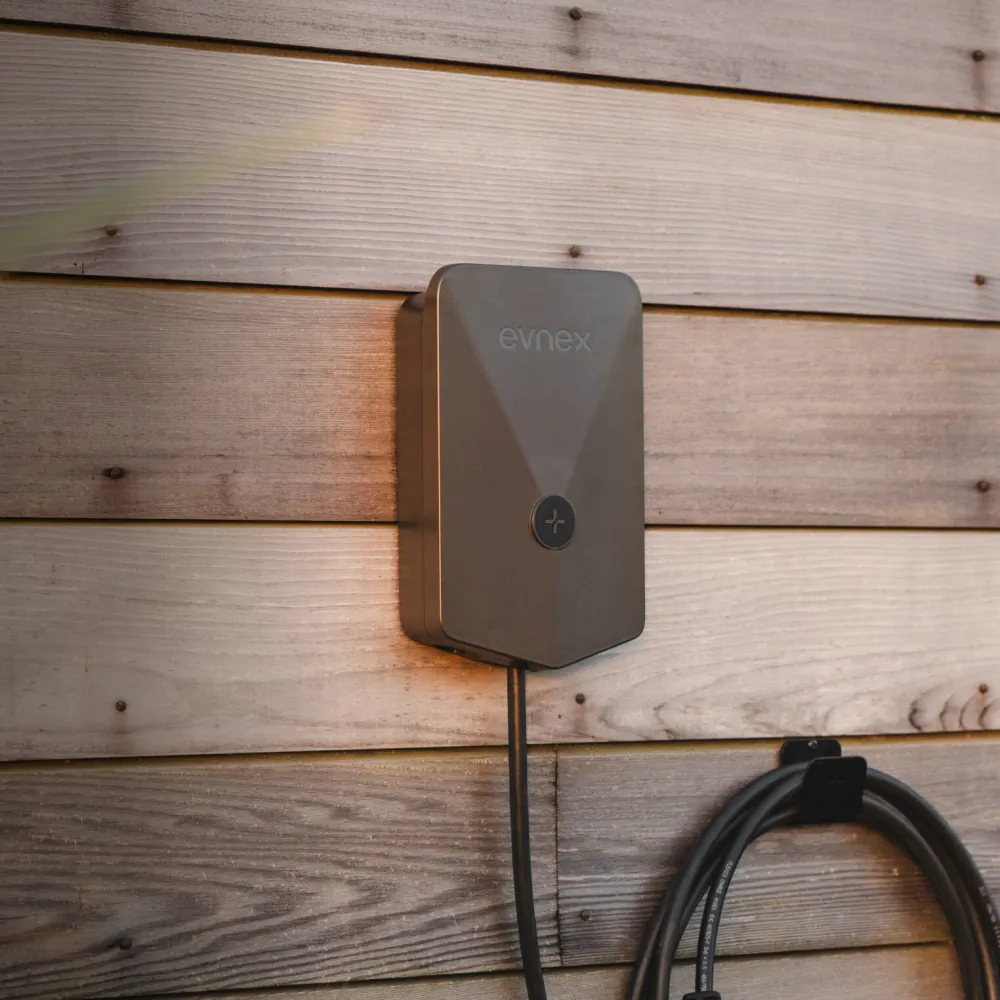 Front view of the Evnex E2 Flex EV charger installed on a timber feature wall with a coiled cable.